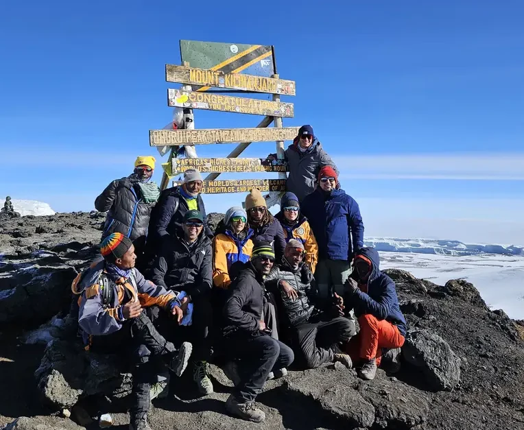 A group with their guides at the summit sign on Kilimanjaro
